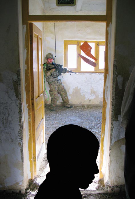 Digging for cover, a soldier from Fourth Platoon, Dagger Company, 2-12 Infantry, presses himself into a corner in an unfinished classroom during a patrol through the Pech Valley.