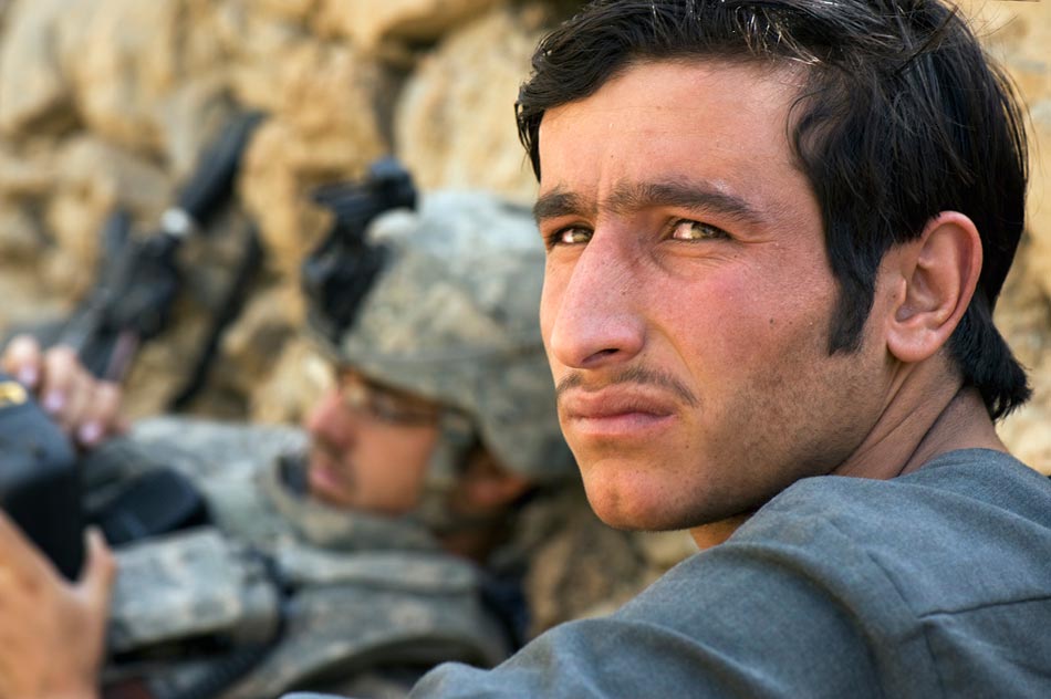 An Afghan civilian waits while a US Army soldier registers his biometric information in a handheld computer, Jalrez Valley, Wardak Province.