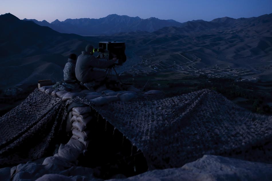 Soldiers use a high-powered night vision device to scan the main road of the Tangi Valley from a mountaintop observation post. The soldiers are looking for insurgents planting IEDs in a road where there have been dozens of attacks since Apache Company arrived in summer 2009.