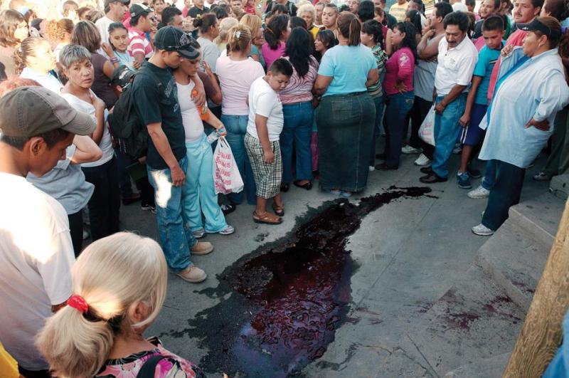 A crowd lingers around the pooled blood of assassinated labor leader Géminis Ochoa, even after his body has been taken away.
