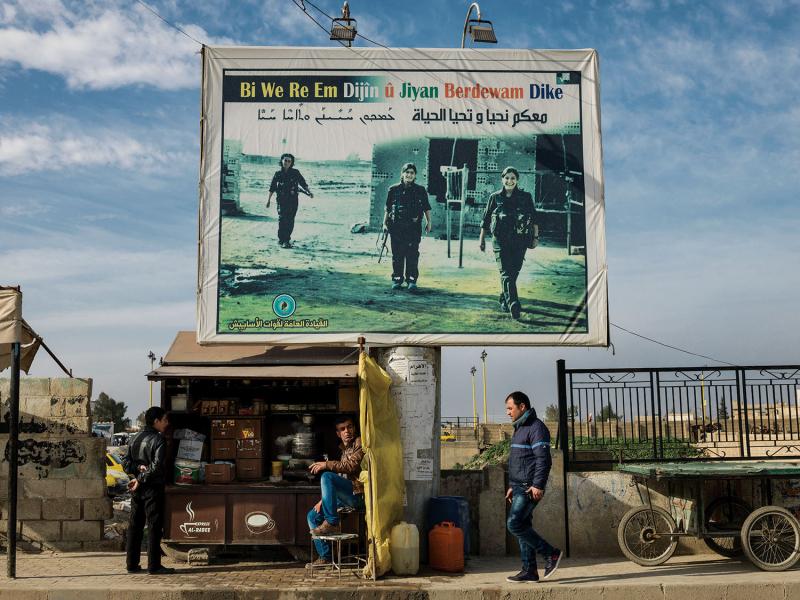 A billboard in Qamishli, Syria, of martyrs who died while fighting ISIS. The billboard reads, “With you we live on and life continues.” (Newsha Tavakolian/Magnum Photos)