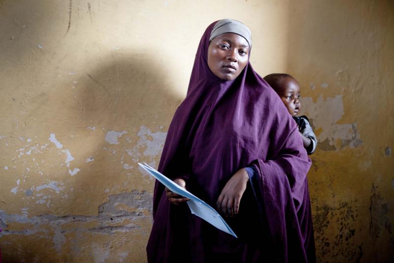 A woman at a clinic in Mogadishu holds the paperwork she will need to complete to receive care for her infant.