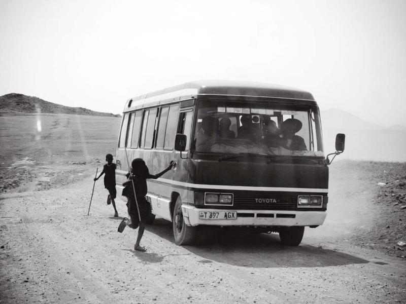 ￼Young Maasai beg for food or change from a bus full of pilgrims on their way to see Reverend Ambilikile Mwasapila, a faith healer in Tanzania’s remote district of Loliondo.