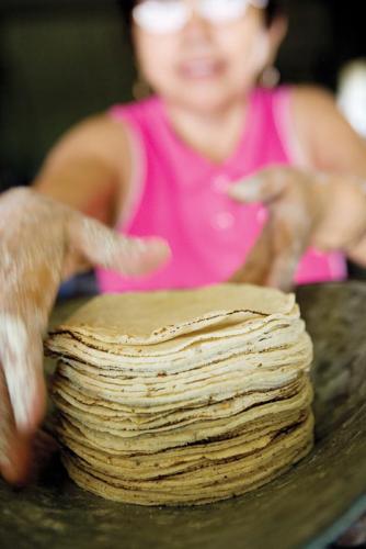 Romero weighs a stack of tortillas at her shop in Pocoboch.